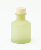 Minimalistisch matgroen glazen huisparfum flesje van 50ml met een houten dop tegen een witte achtergrond.