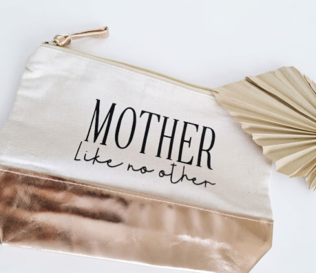 Canvas toilettas met koperkleurige onderzijde en tekst 'MOTHER Like no other' naast een decoratieve waaier.