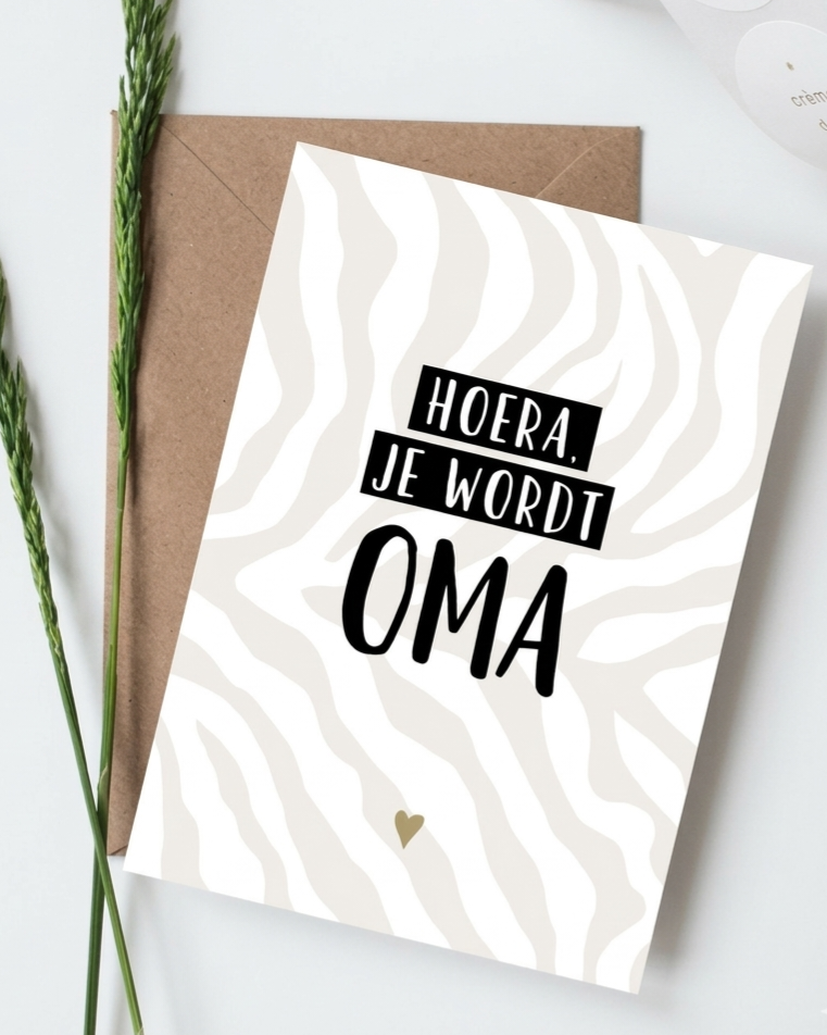 Moderne witte kaart met zebraprint en zwarte tekst 'Hoera, je wordt OMA', liggend op een bruine kraft envelop.