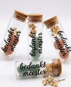 vier glazen buisjes met kurkenstop gevuld met droogbloemen en bloembollen, bedrukt met de tekst bedankt meester in zwart