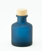Minimalistisch matblauw glazen roomspray flesje van 50ml met een houten dop tegen een witte achtergrond.