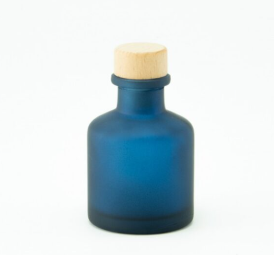 Minimalistisch matblauw glazen roomspray flesje van 50ml met een houten dop tegen een witte achtergrond.